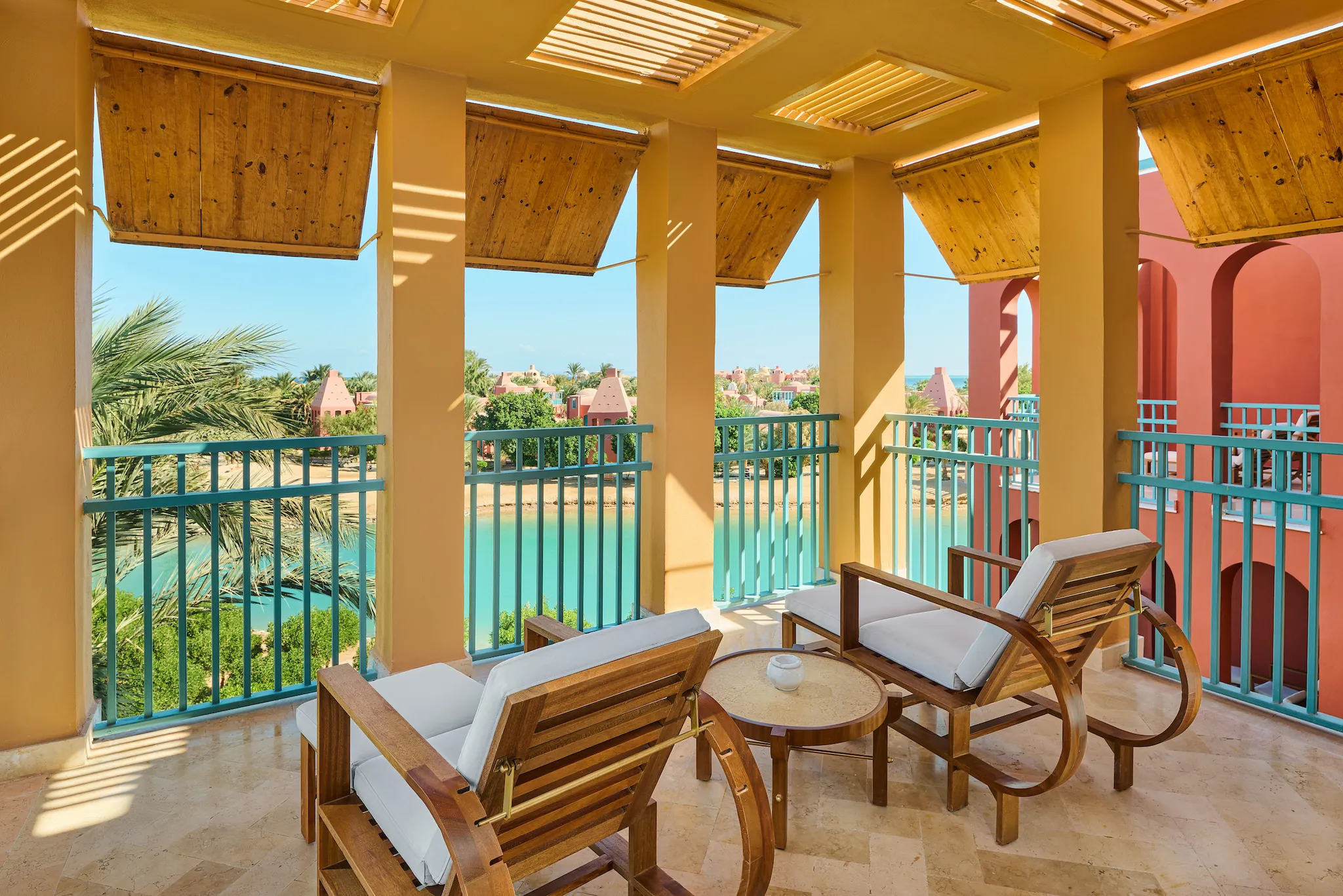 Covered balcony terrace with wooden lounge chairs and turquoise railings overlooking the resort lagoon at Sheraton Miramar Resort El Gouna