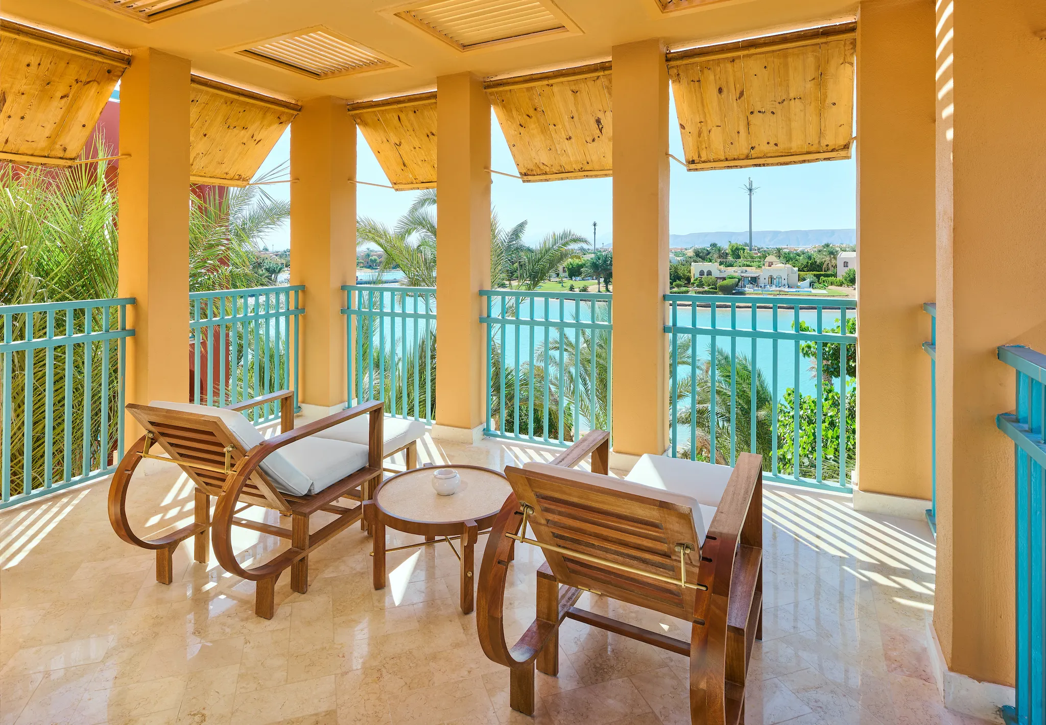Spacious covered suite terrace with wooden loungers, side table, and panoramic views of the lagoon at Sheraton Miramar Resort El Gouna