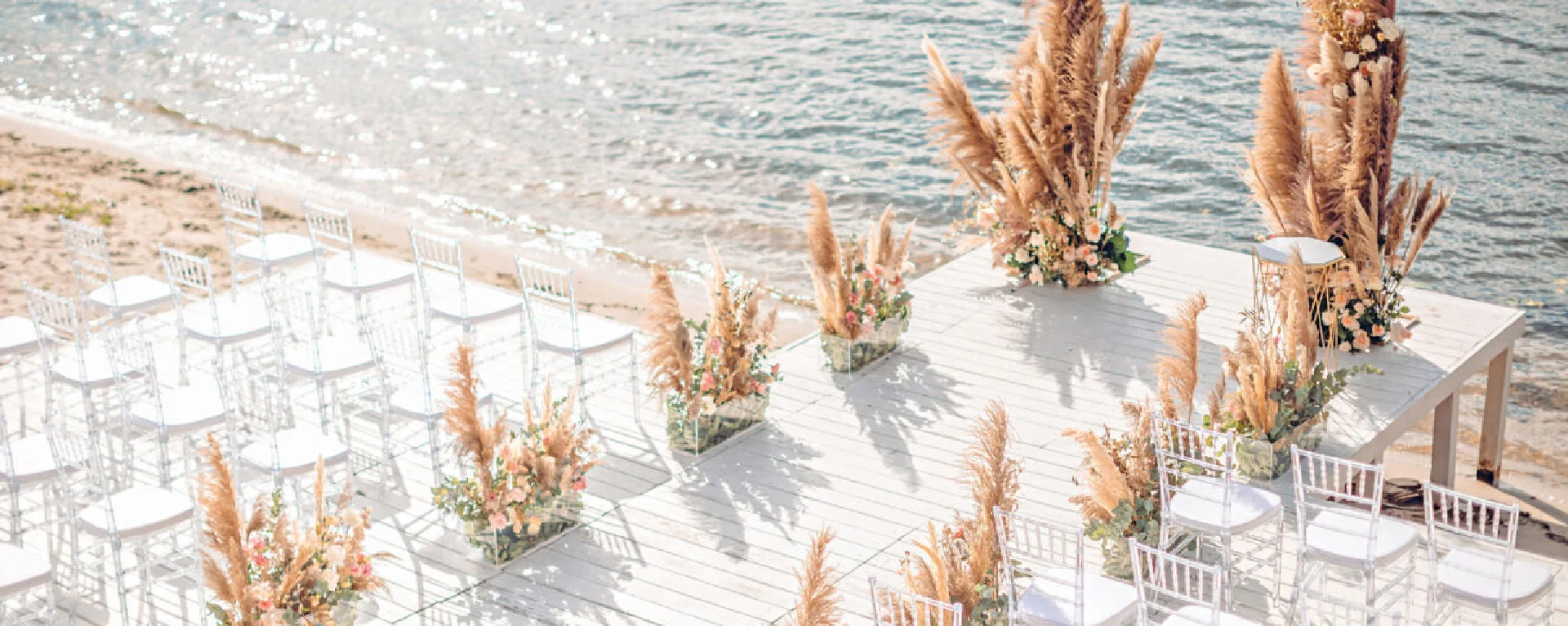 Scenic beach wedding setup at Chedi El Gouna, featuring rows of white chairs arranged on the sandy shore with a view of the sea.