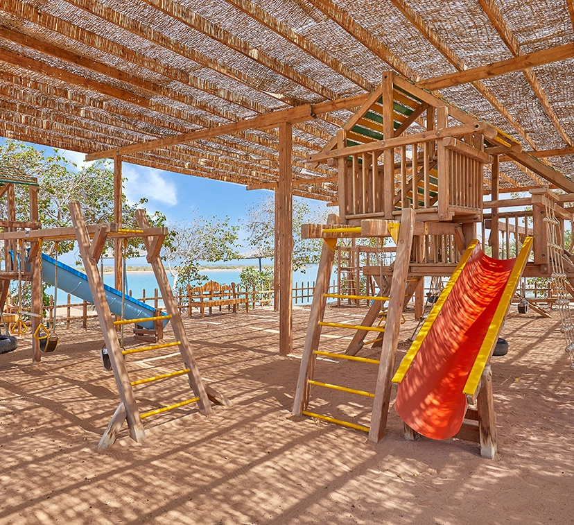 The kids' area at Sheraton Miramar, featuring colorful and engaging play equipment. The space includes a variety of attractions such as slides, climbing structures, and interactive games. The area is designed with vibrant colors and safe surfaces, and is surrounded by lush landscaping, creating a fun and welcoming environment for children.