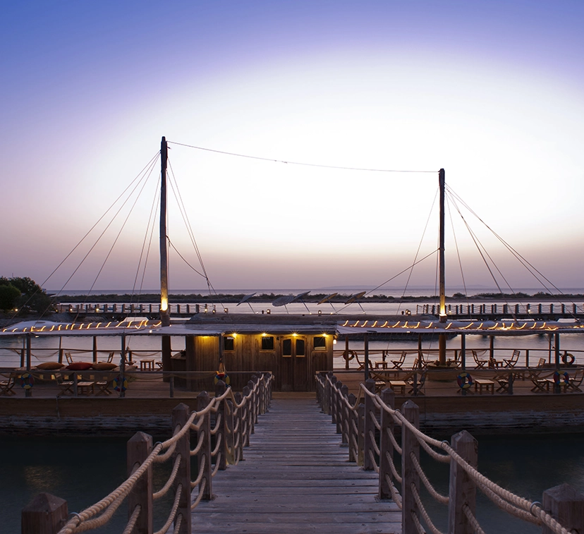 A romantic dining setup at Sheraton Hotel, featuring a beautifully set table for two. The table is adorned with a white tablecloth, elegant dinnerware, glassware, and candles, creating a soft, intimate glow. The setting is enhanced with fresh flowers and a view of a scenic backdrop, such as a sunset or garden, adding to the romantic ambiance.