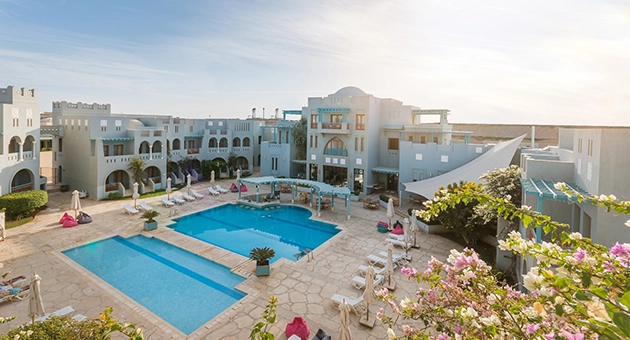 The Fanadir Hotel's courtyard features Mediterranean-style buildings with vibrant bougainvillea.