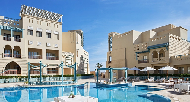Serene pool area at Mosaique Hotel El Gouna, featuring clear blue water under a sunny sky.