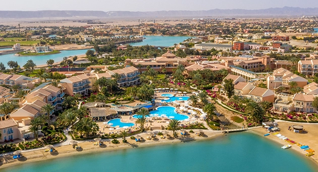 Aerial view of Mövenpick Hotel El Gouna with terracotta-roofed buildings, pools, lush greenery, and beachfront along the Red Sea.