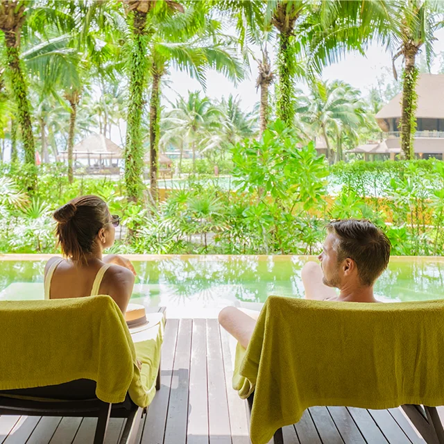 Couple enjoying the poolside, relaxing on sun lounges.