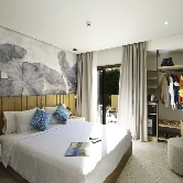 Elegant hotel room at night featuring a king-size bed, and open balcony curtains that allow a glimpse of the nighttime ambiance outside. The interior is beautifully decorated with stylish furnishings and soft lighting, creating a cozy and sophisticated atmosphere.