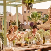 A couple enjoying the dining experience at The Three Corners Rihana Resort. They are seated at an elegantly set table with dishes and drinks. The stylish and inviting ambiance enhances their dining experience.