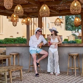 A young couple leaning at the bar, enjoying drinks and the lively atmosphere at the hotel. The setting is stylish and vibrant, enhancing their experience.