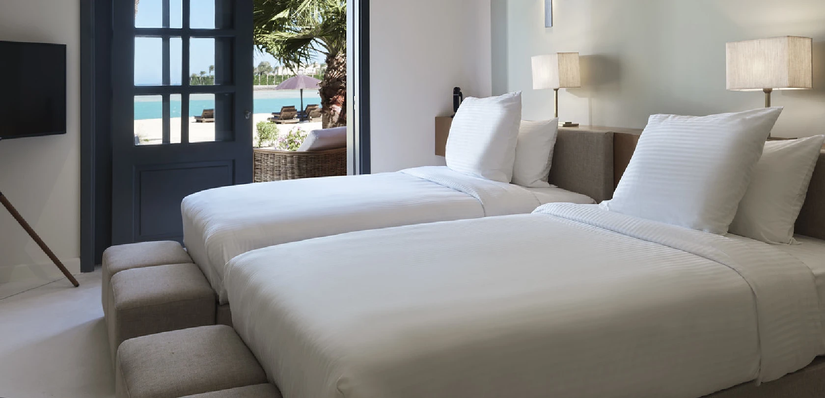 Twin bedroom with open balcony, featuring two beds, modern decor, and a view of the outdoors.