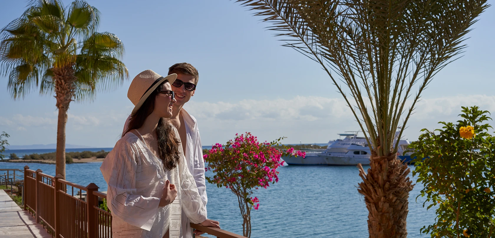 A couple shares a romantic moment framed by the expansive sea and a luxurious yacht in the background, capturing the essence of serene beauty and tranquility.