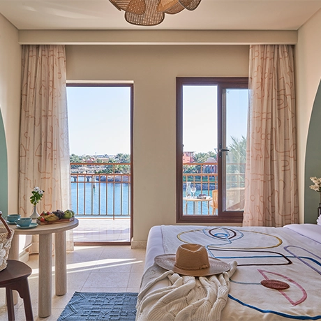 A spacious Superior Room with a king-sized bed at Three Corners Ocean View, El Gouna, Red Sea. The room offers a stunning sea view from a private balcony, featuring modern furnishings, soothing neutral tones, and large windows that flood the space with natural light.