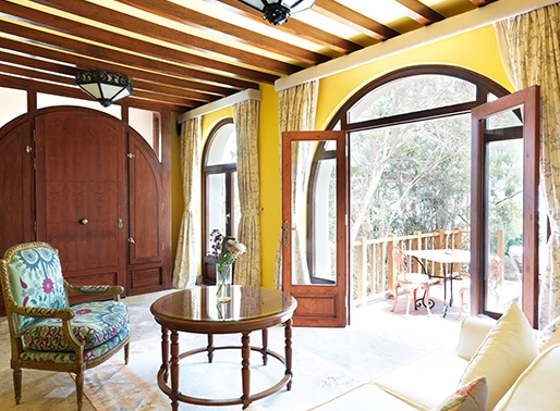 The Premium Suite at La Maison Bleue, showcasing a luxurious and spacious interior. The suite features a plush king-size bed, a separate sitting area with stylish furniture, and a well-appointed bathroom. Large windows or a private balcony offer beautiful views of the surrounding landscape. The decor includes elegant finishes and a refined color palette, providing a comfortable and upscale atmosphere.