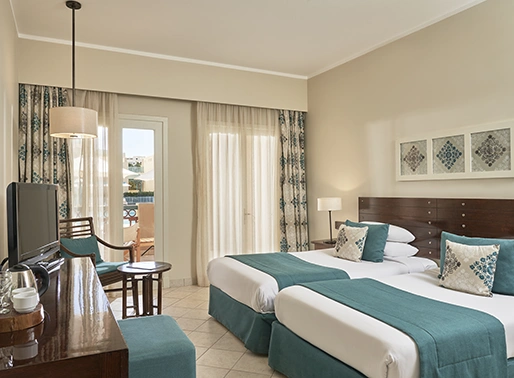 Twin bedroom at Red Sea, Egypt, featuring two single beds with crisp linens, modern decor, and stylish furnishings. The room is bright and inviting, designed for comfort and relaxation, with a warm color palette and ample amenities.