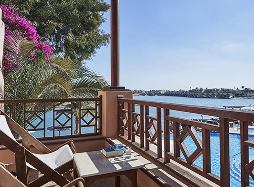 Sea view balcony of a room at El Gouna Red Sea, Egypt, featuring a comfortable lounge area. The balcony includes plush outdoor seating and a table, offering stunning views of the sea. The space is designed for relaxation, with stylish furnishings and a serene ambiance.