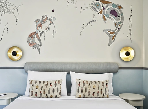 Marina room at Turtle's Inn featuring a large, comfortable bed and wall art with fish designs, creating a vibrant and cozy marine-themed atmosphere.